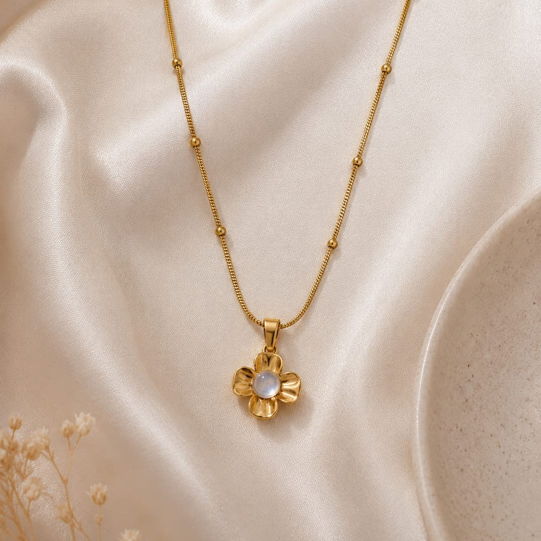 Gold necklace with a floral pendant on a beige fabric background